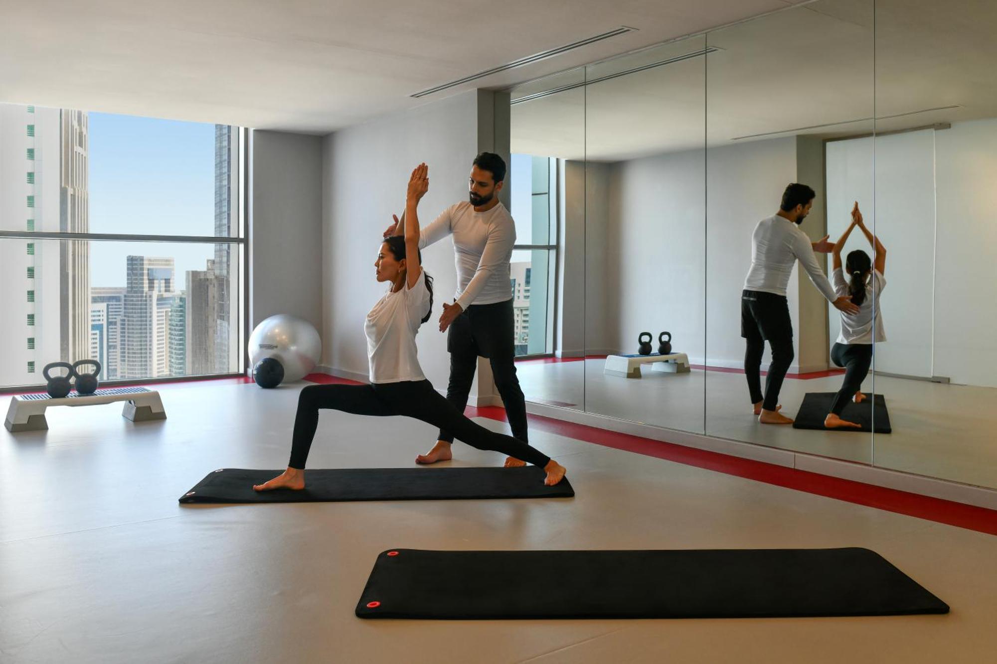 Dusit Doha Hotel Buitenkant foto A personal trainer assisting a woman with a yoga workout